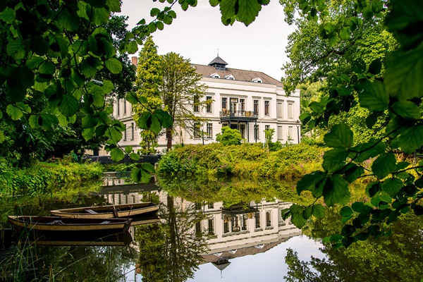 Rückseite von Schloss De Berckt in Baarlo mit Booten auf dem Wasser