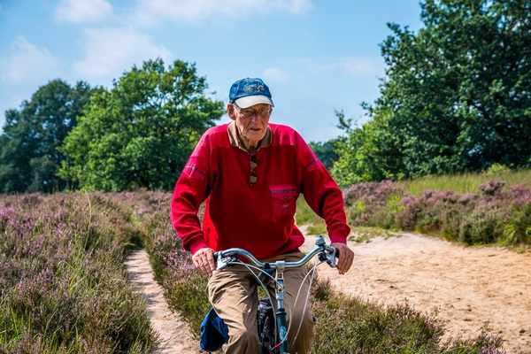 Elderly man cycles along a dirt track through De Meinweg National Park